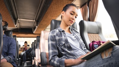 Reisende liest Buch während Reise im Reisebus