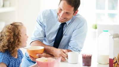 Vater lächelt am Frühstückstisch seiner Tochter zu