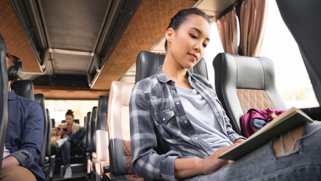 Frau liest Buch während Reise im Reisebus